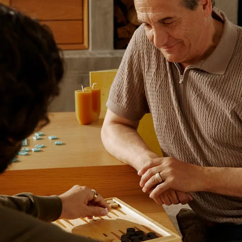 Older man smiles while playing a board game with another person at home together | Smartring PH
